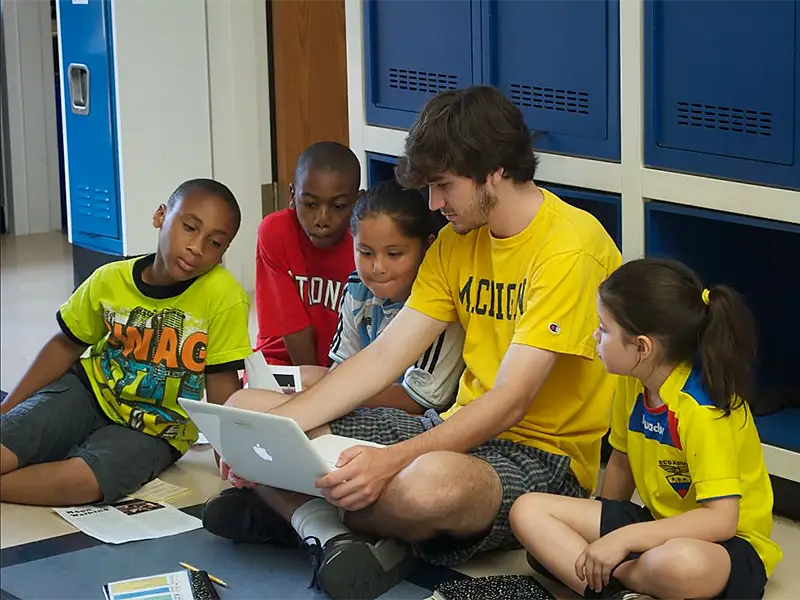 Michael in hallway with group of students looking at computer
